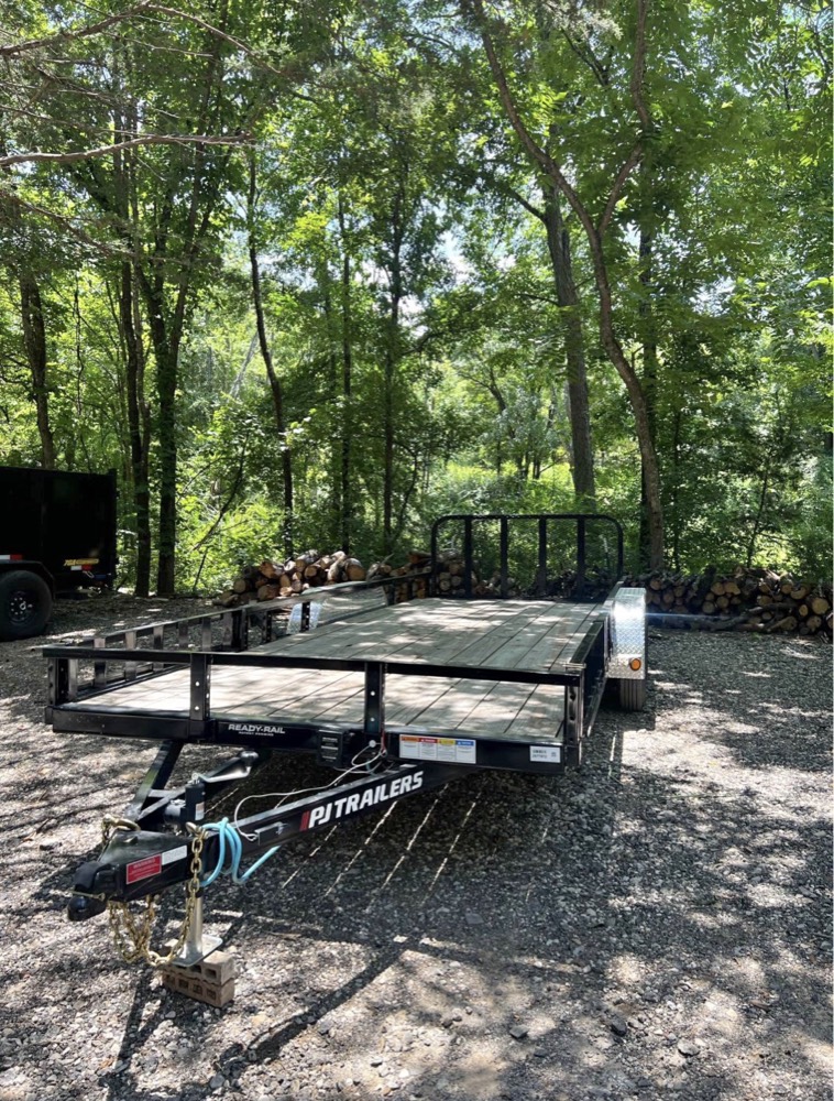 PJ Trailers 20ft utility trailer with removable side rails, parked on a gravel lot